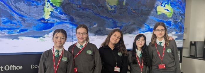 Cranrbook Students stood infront of a world map background visisting the Met Office